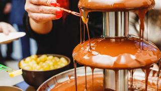 Person beim kosten von Schokolade für Schokobrunnen