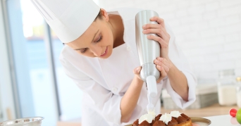 Sahnespender Köchin bei Verwendung eines Sahnespenders